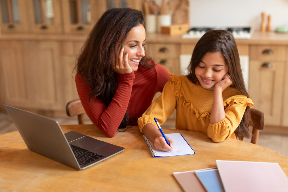 Mommy hugging her smart daughter while she writing homework indoor