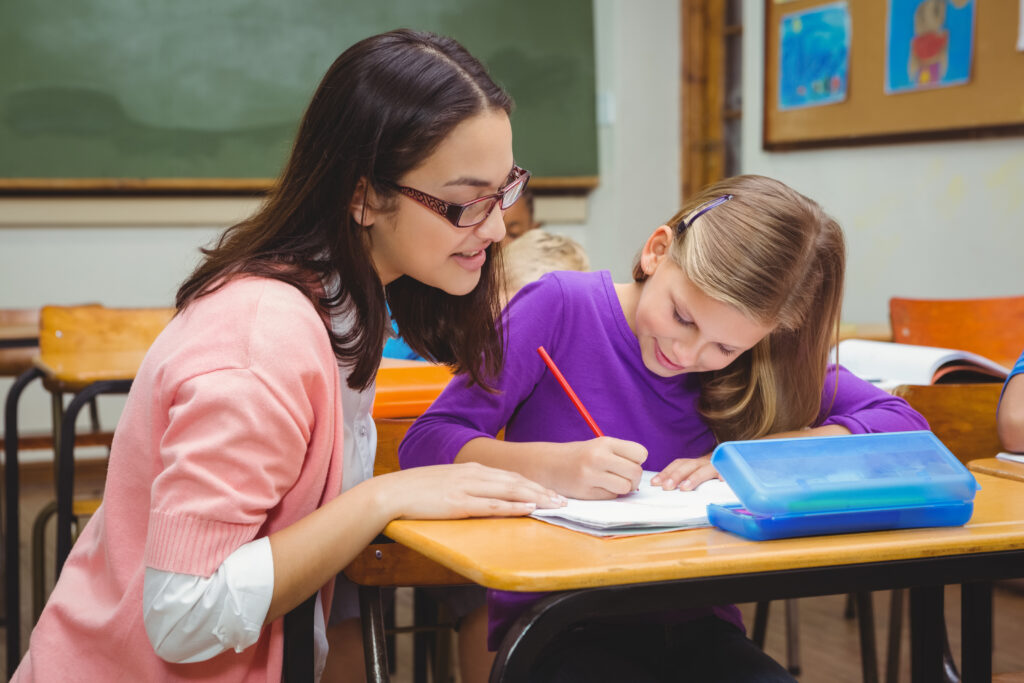Happy teacher helping her students at the elementary school